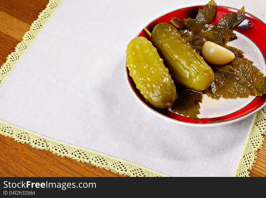 Marinated cucumbers on plate with garlic and currant leaf