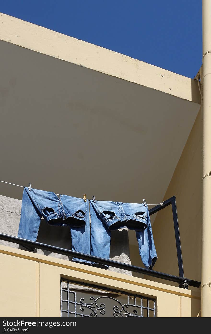 Two pairs of blue jeans drying on balcony sunlight. Two pairs of blue jeans drying on balcony sunlight