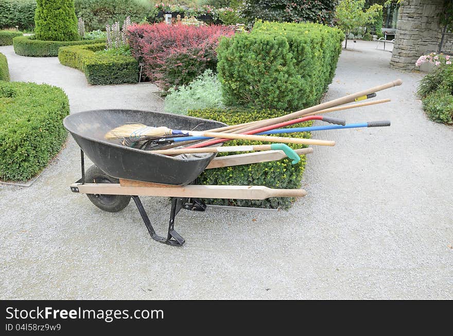 Wheelbarrow with garden tools in formal garden