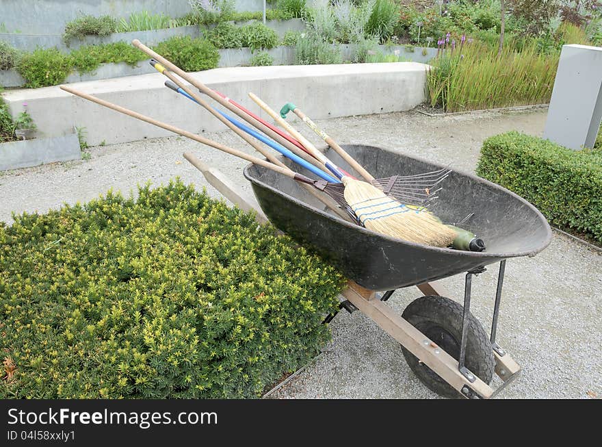 Wheelbarrow with garden tools in formal garden