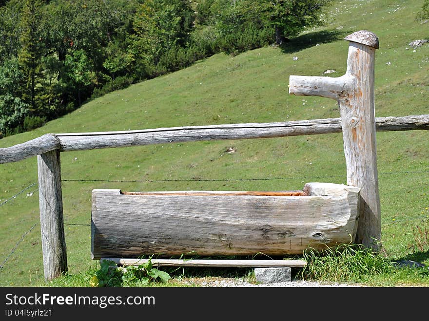 Wooden trough in the German Alps area, surrounded by green grass and trees. Wooden trough in the German Alps area, surrounded by green grass and trees