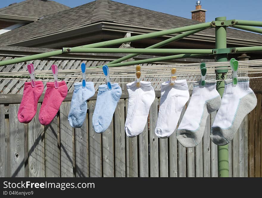 Pink,blue,white and grey socks on a clothesline hanging to dry outside. Pink,blue,white and grey socks on a clothesline hanging to dry outside