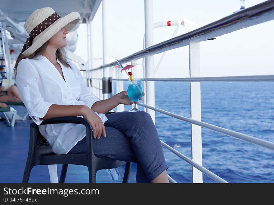 A woman in a hat and a cocktail  on the liner