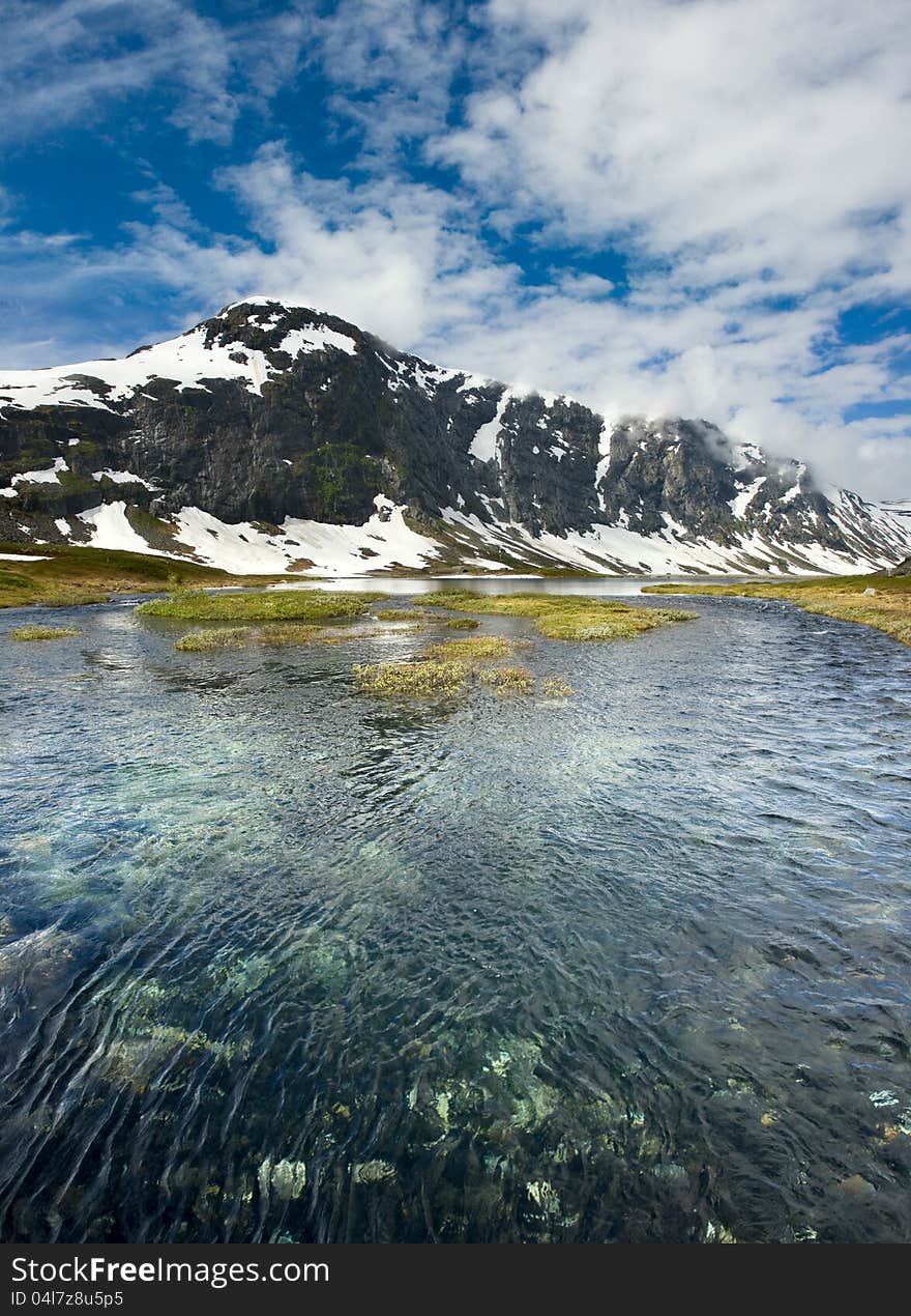 Norwegian landscape with a mountain on background and mountain river.