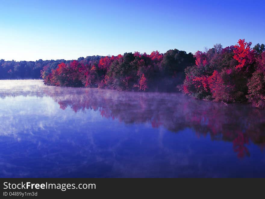 Image taken from highway overpass over the river overlooking these beautiful tree colors reflecting of calm early morning waterflow. Image taken from highway overpass over the river overlooking these beautiful tree colors reflecting of calm early morning waterflow