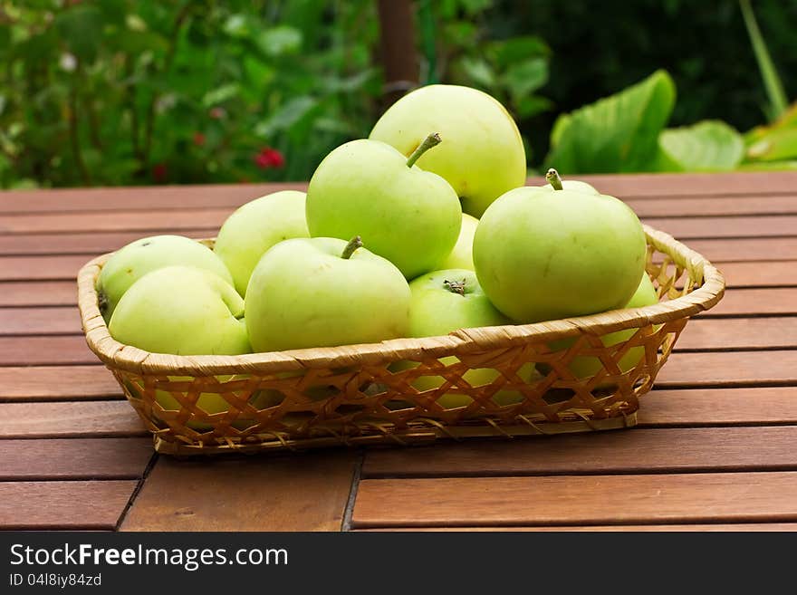 Fresh green apples in bucket on wooden surface