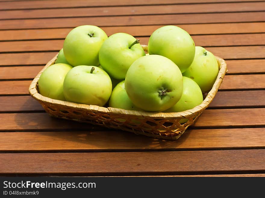 Set of fresh green apples in bucket on wooden background