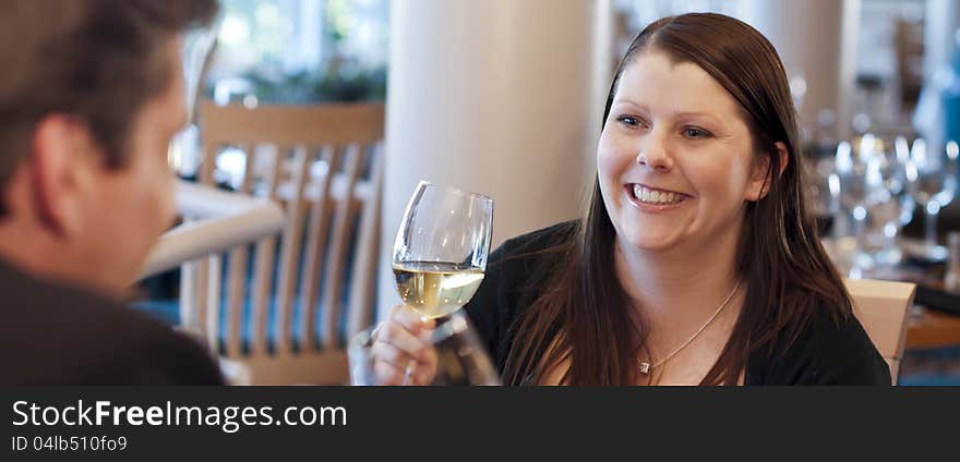 Couple in restaurant drinking wine and smiling. Focus on woman