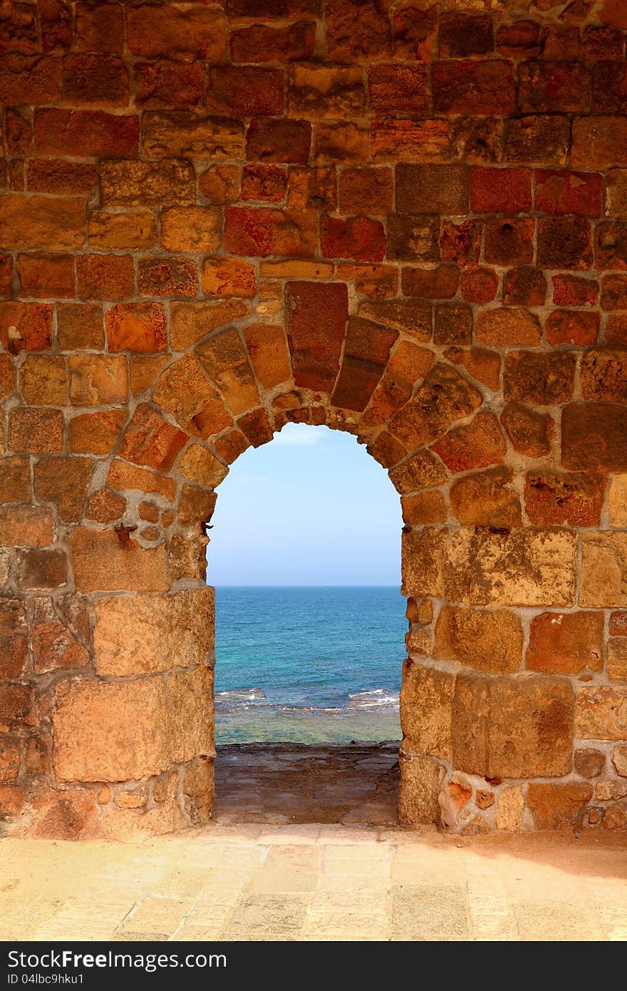 View on the dark blue sea through a window in an old fortification. View on the dark blue sea through a window in an old fortification