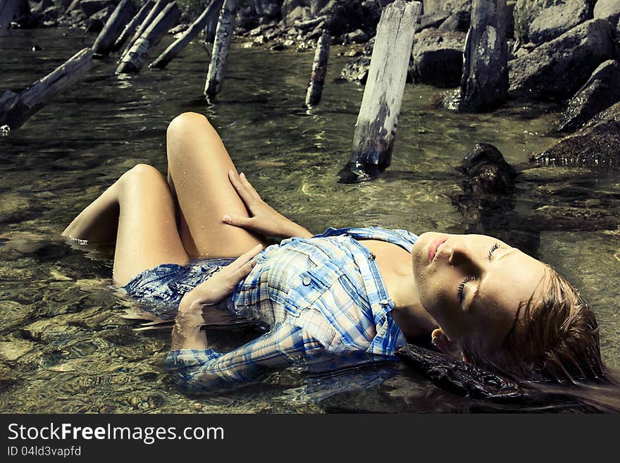 Fashion photo of young beautiful woman lying in water with eyes closed