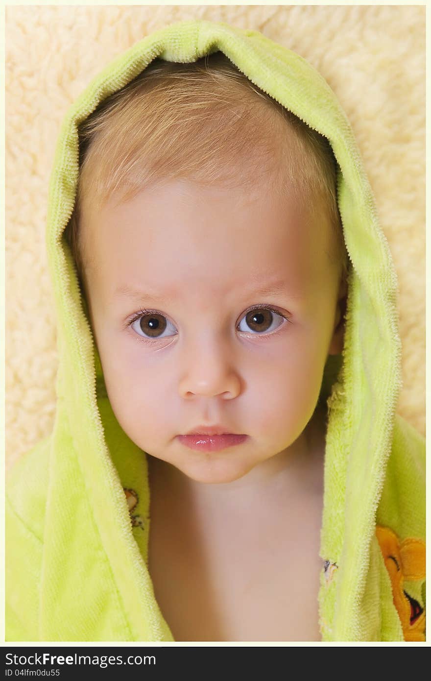 The kid in a bathing dressing gown sits. The kid in a bathing dressing gown sits