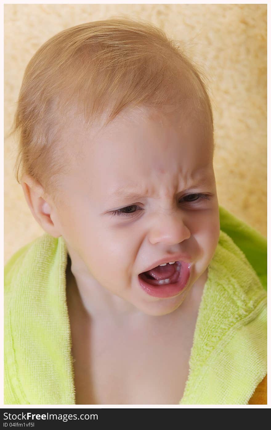 Close up a face of the kid which cries in a bathing dressing gown. Close up a face of the kid which cries in a bathing dressing gown