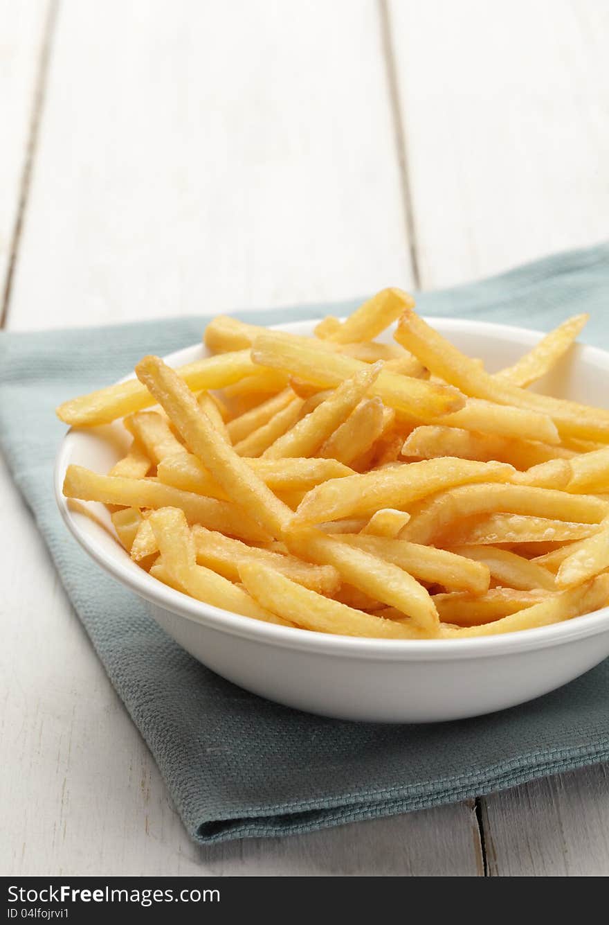 Bowl of french fries on white wooden surface. Bowl of french fries on white wooden surface