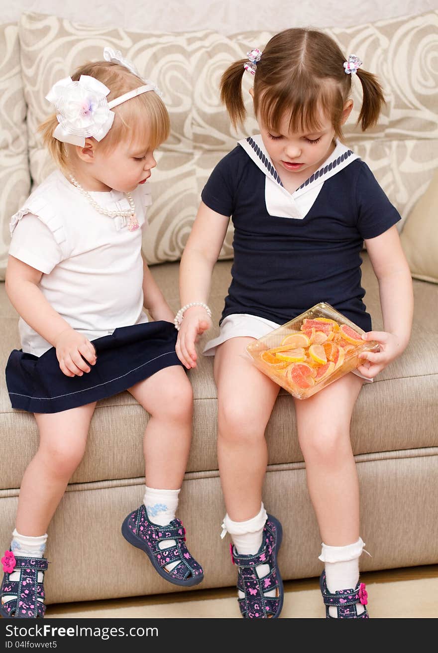 Two little girls eat candies