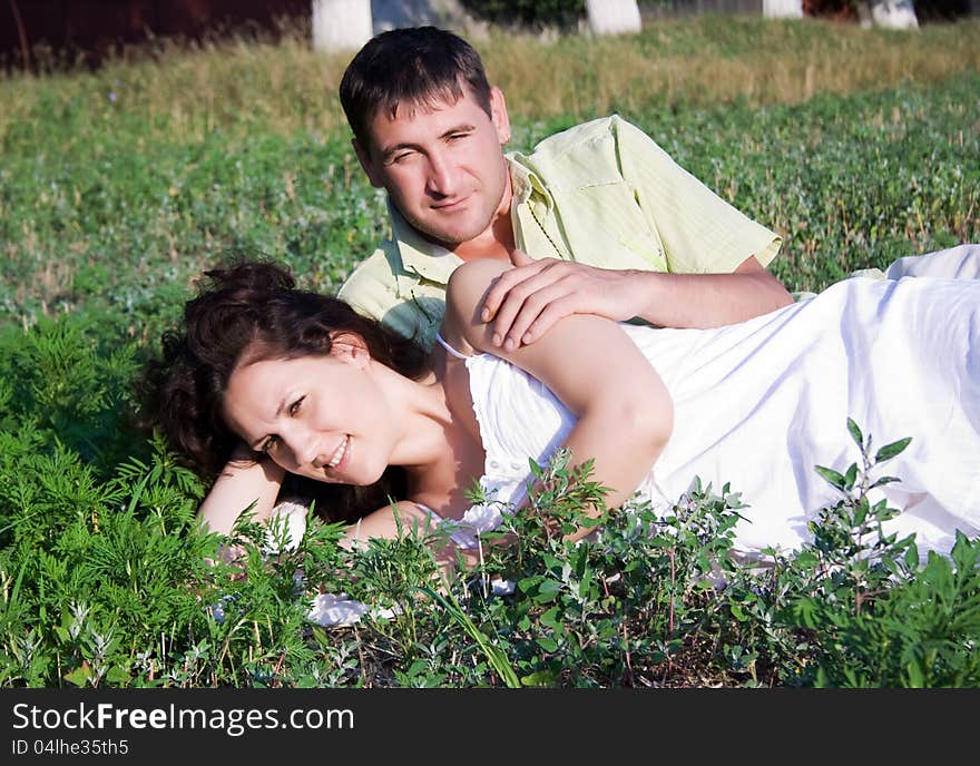 Portrait of a pretty young women lying on grass with her boyfriend in the park - Outdoor. Portrait of a pretty young women lying on grass with her boyfriend in the park - Outdoor