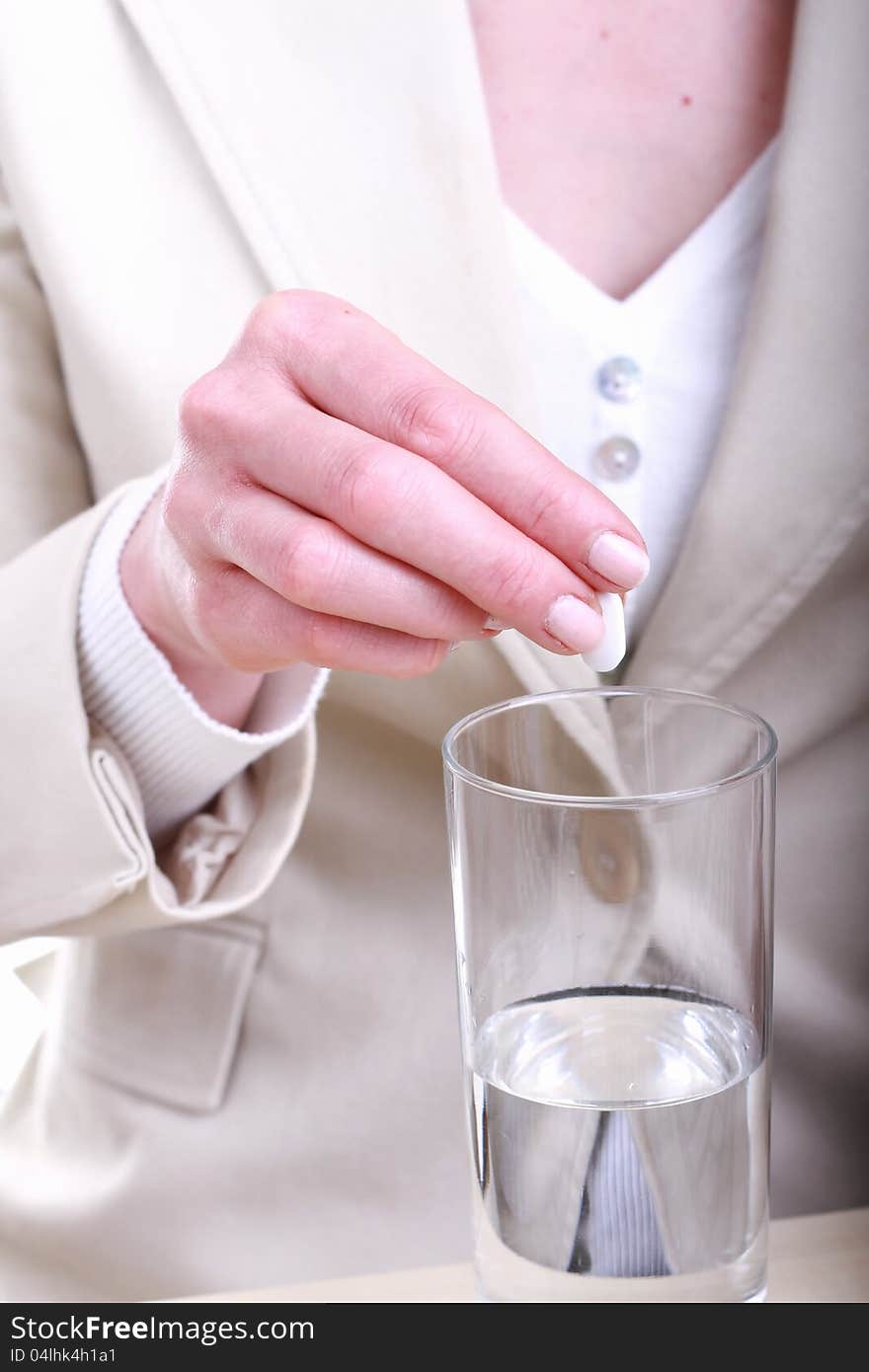 Image of a young woman taking a painkiller after a long day. Image of a young woman taking a painkiller after a long day