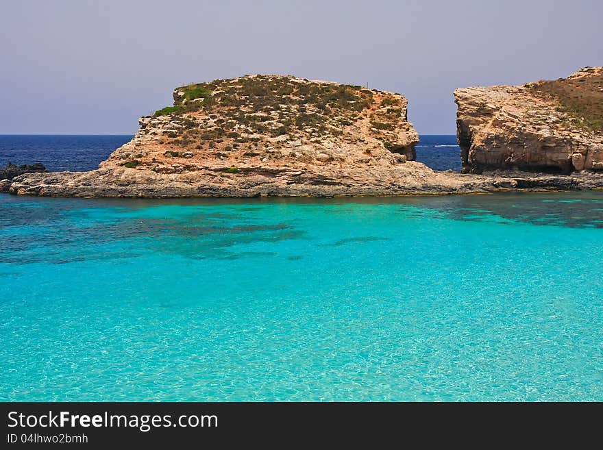 A view of perfect turquoise sea water with rocks in background. A view of perfect turquoise sea water with rocks in background.