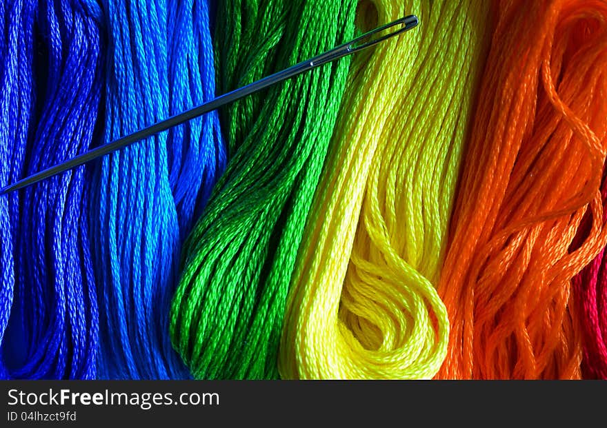 Vertical color photo of a rainbow of threads with a needle. Vertical color photo of a rainbow of threads with a needle.