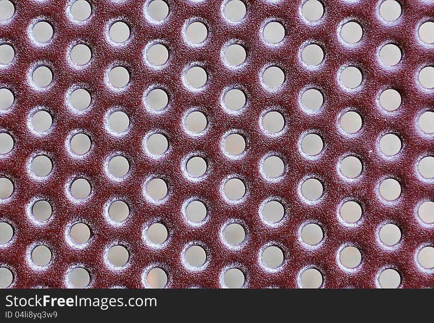 Red metal grate with a repeating hole patern for use as a background. Red metal grate with a repeating hole patern for use as a background