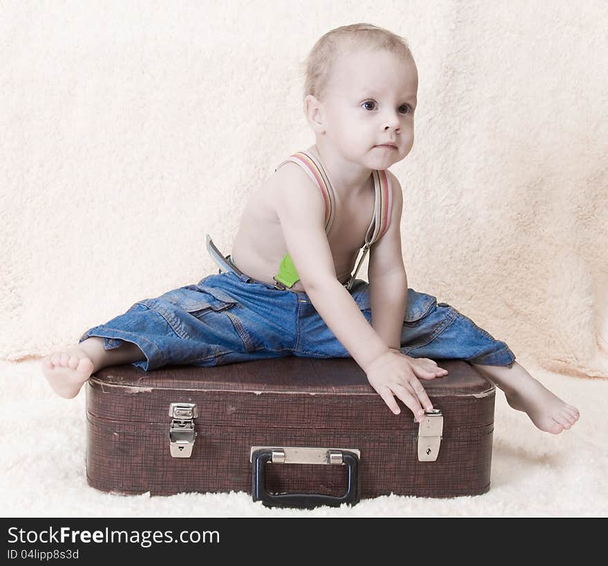 The child in jeans sits on an old suitcase. The child in jeans sits on an old suitcase