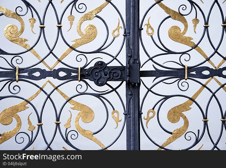 Detail of black and golden ornamental iron wrought gate. Detail of black and golden ornamental iron wrought gate.