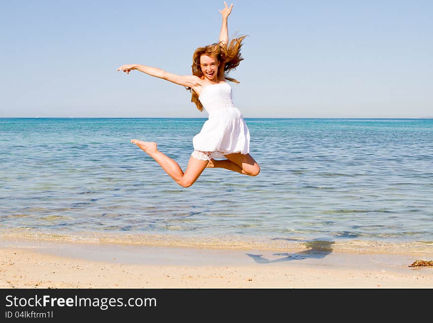 Happy young woman jumping on the beach