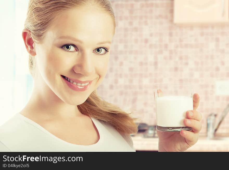 Beautiful healthy girl with a glass of milk in the kitchen at home