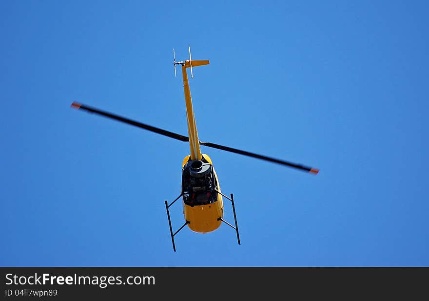 A helicopter in flight against a blue background.