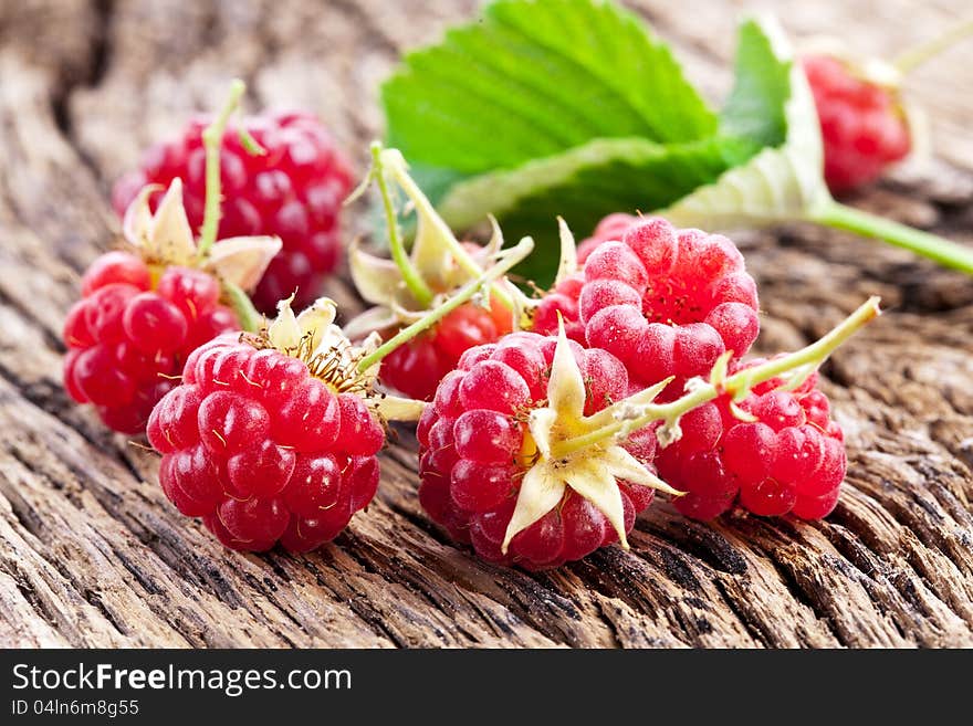 Raspberries with leaves on the old wooden table.