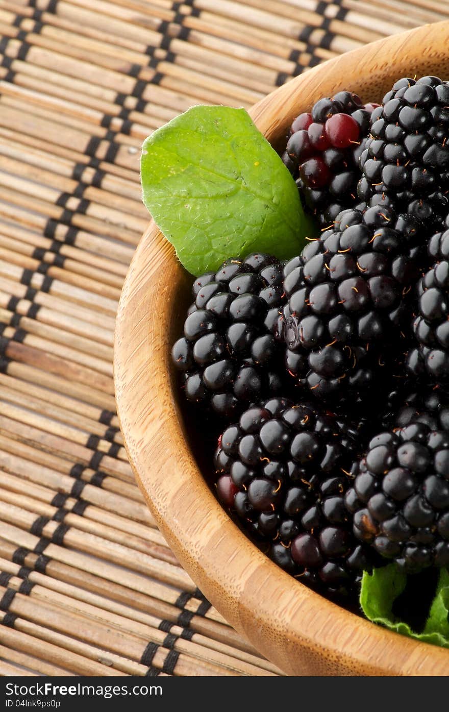 Perfect Blackberries in Wooden Bowl close up on Strawmat background