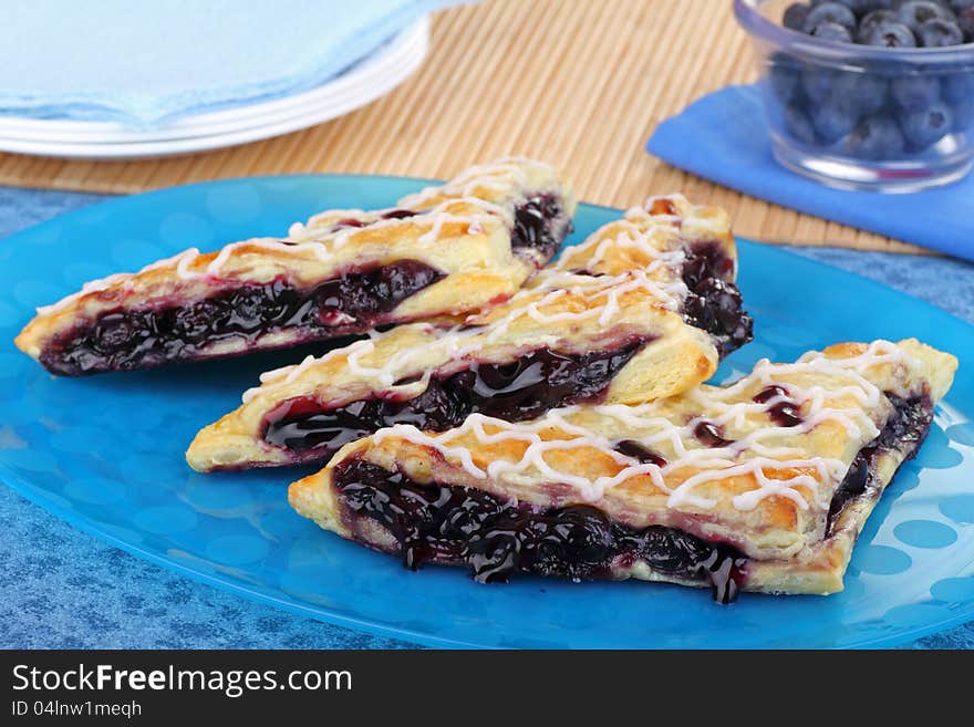 Three blueberry turnovers on a blue platter