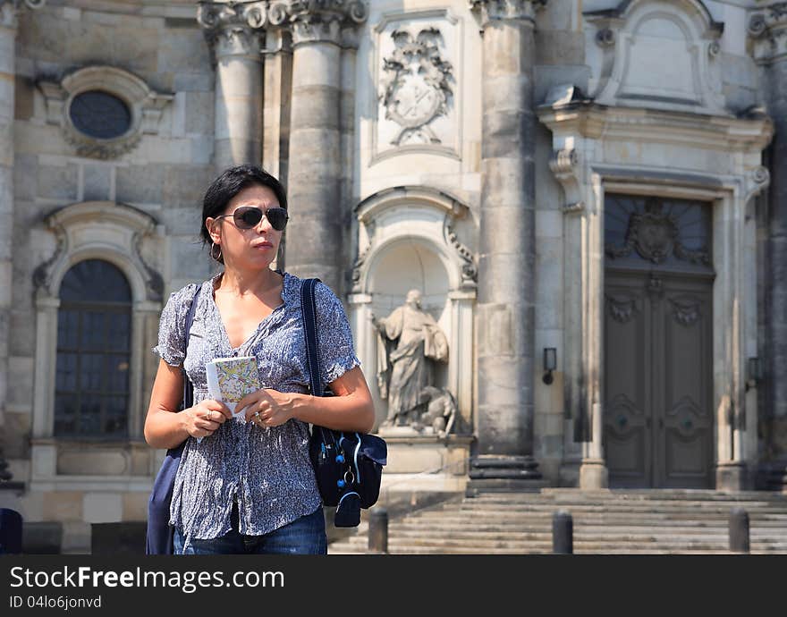 Sightseeng concept.Attractive mature woman holding a city map on street against ancient building. Sightseeng concept.Attractive mature woman holding a city map on street against ancient building