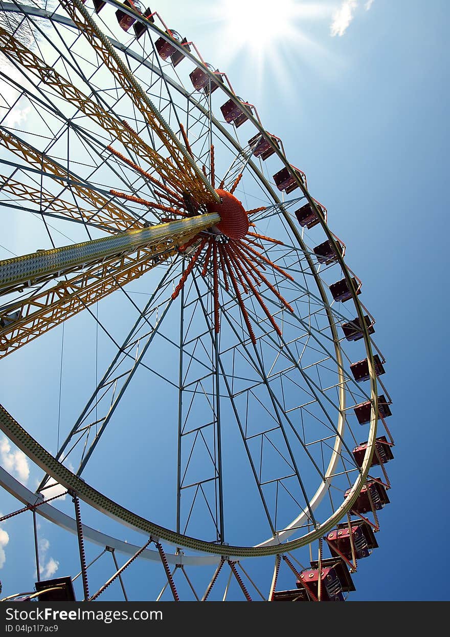 Ferris wheel in the background of blue sky and sun