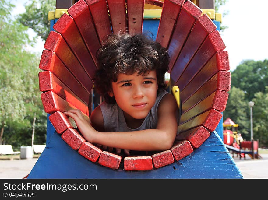 Curly boy is playing on the playground