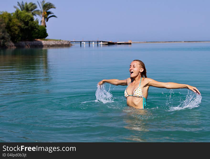 Happy young woman playing in the sea