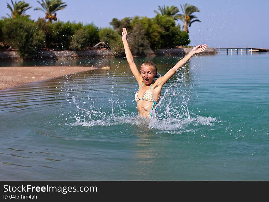 Happy young woman playing in the sea