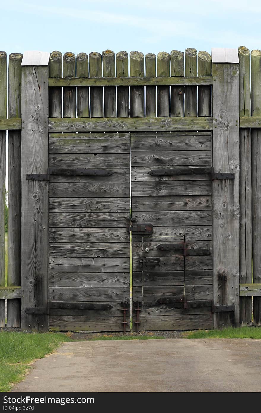 Very large historic gate a few hundred years old and standing at least 10 feet tall under a partly sunny sky. Very large historic gate a few hundred years old and standing at least 10 feet tall under a partly sunny sky.