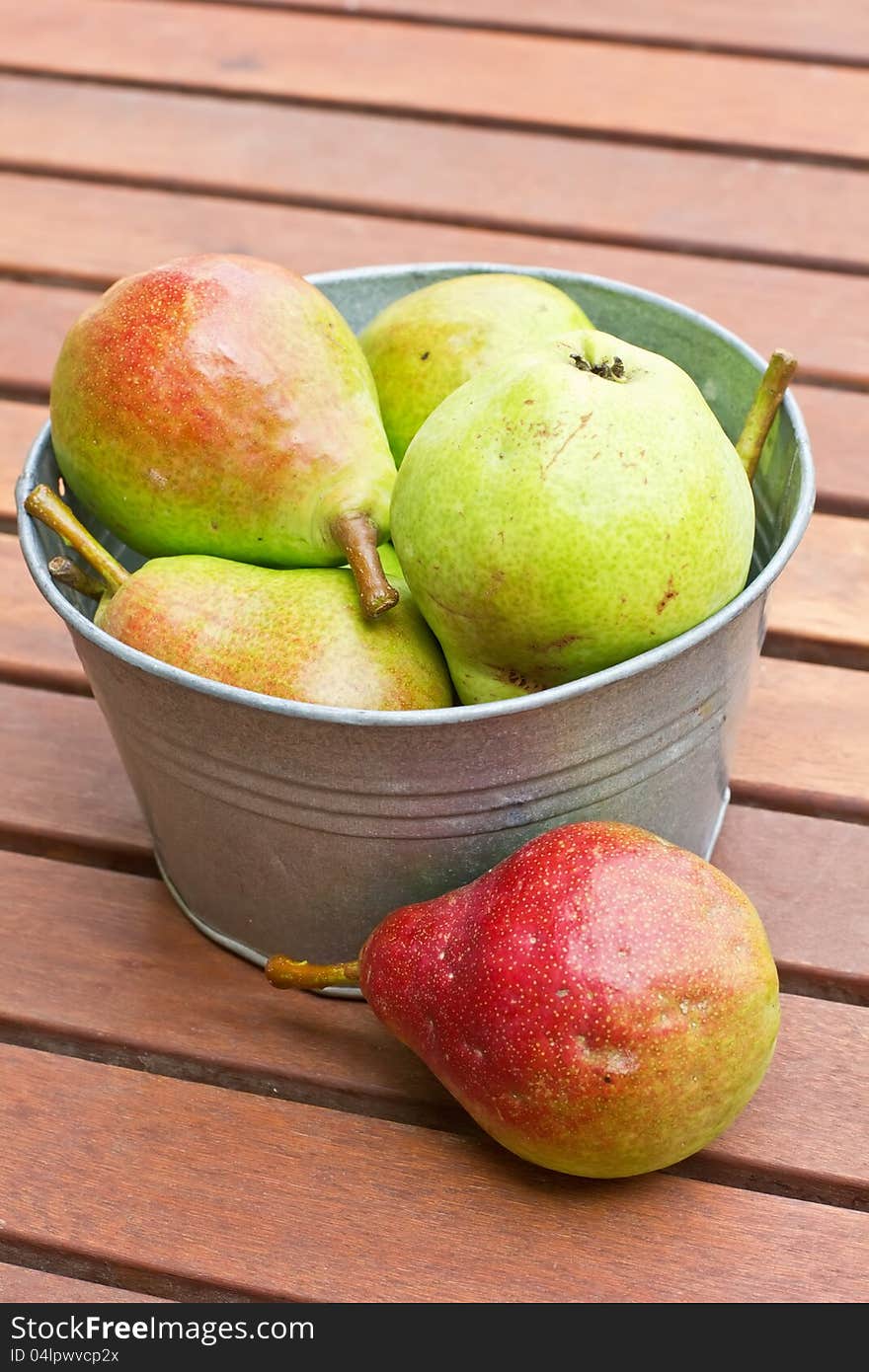 Fresh colourful organic pears in old metallic bowl on wooden surface. Fresh colourful organic pears in old metallic bowl on wooden surface