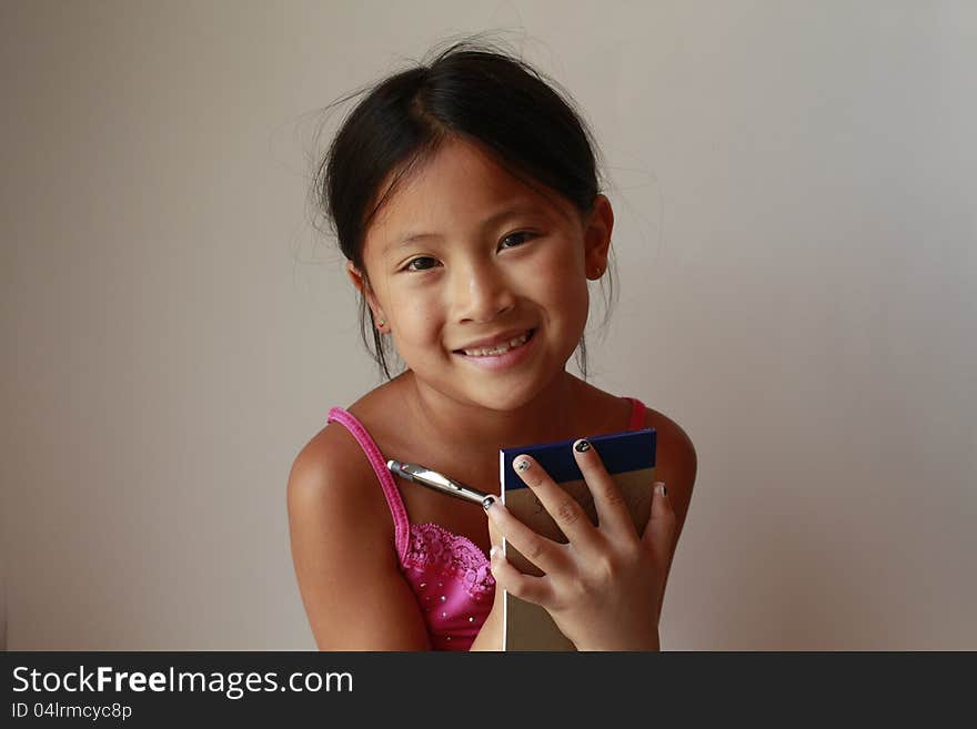 Little Chinese girl holding writing pad and pen. Little Chinese girl holding writing pad and pen