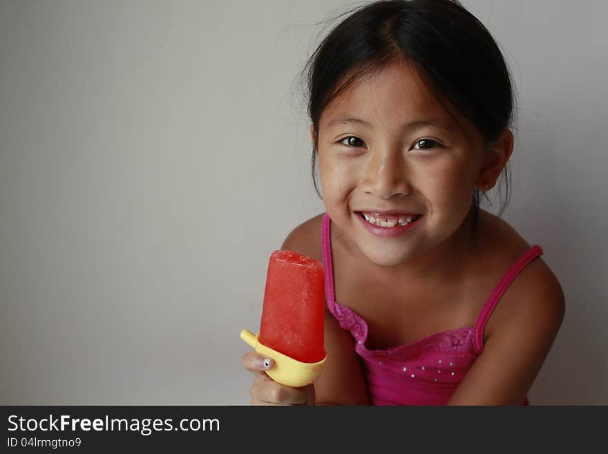 Happy little Chinese girl eating a ice pop. Happy little Chinese girl eating a ice pop