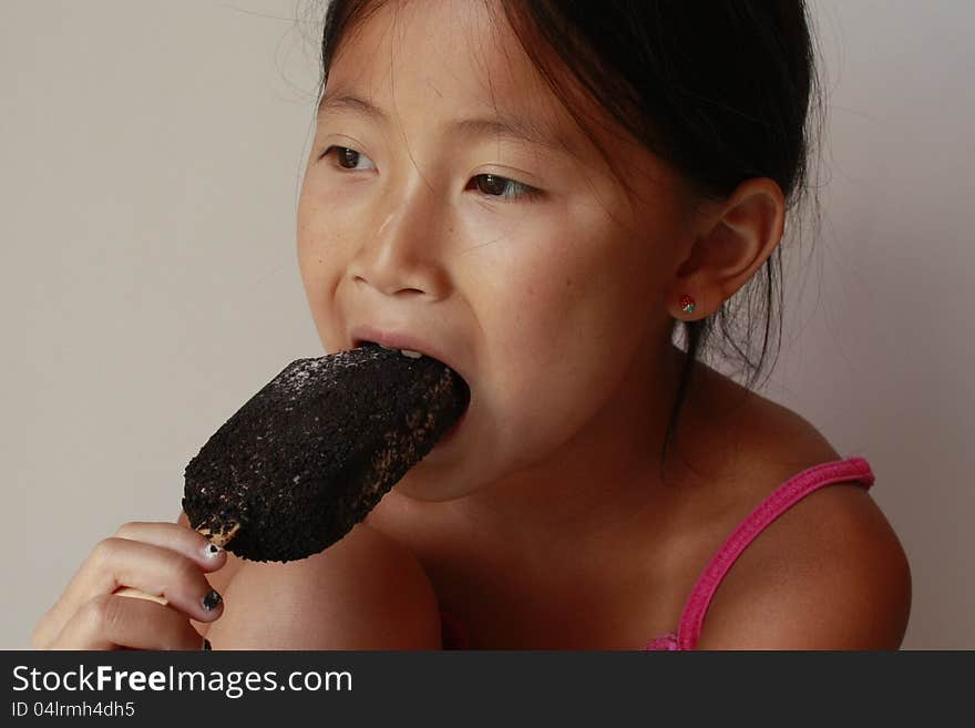Happy little Chinese girl eating a ice cream pop. Happy little Chinese girl eating a ice cream pop