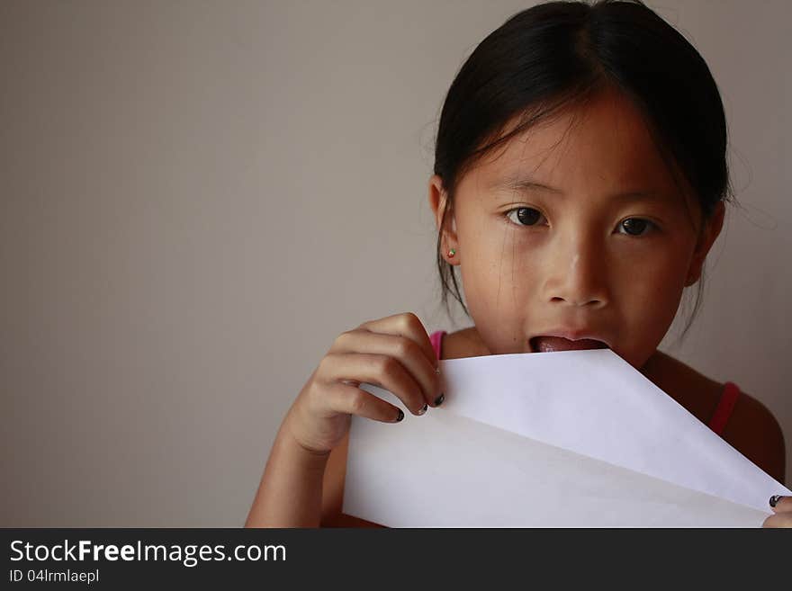 Little asian girl licking a envelope