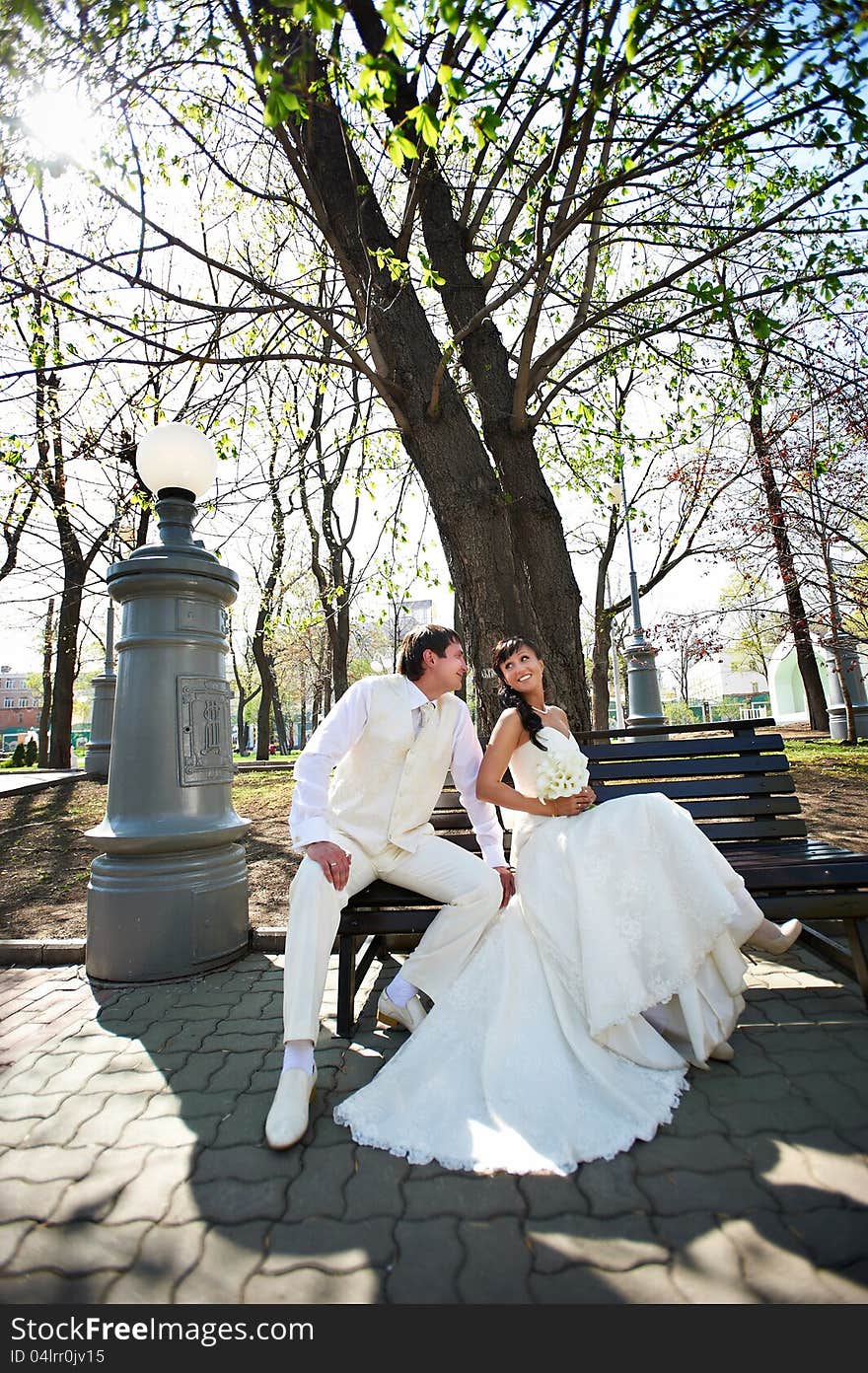 Happy bride and groom on decorative bench at wedding walk. Happy bride and groom on decorative bench at wedding walk