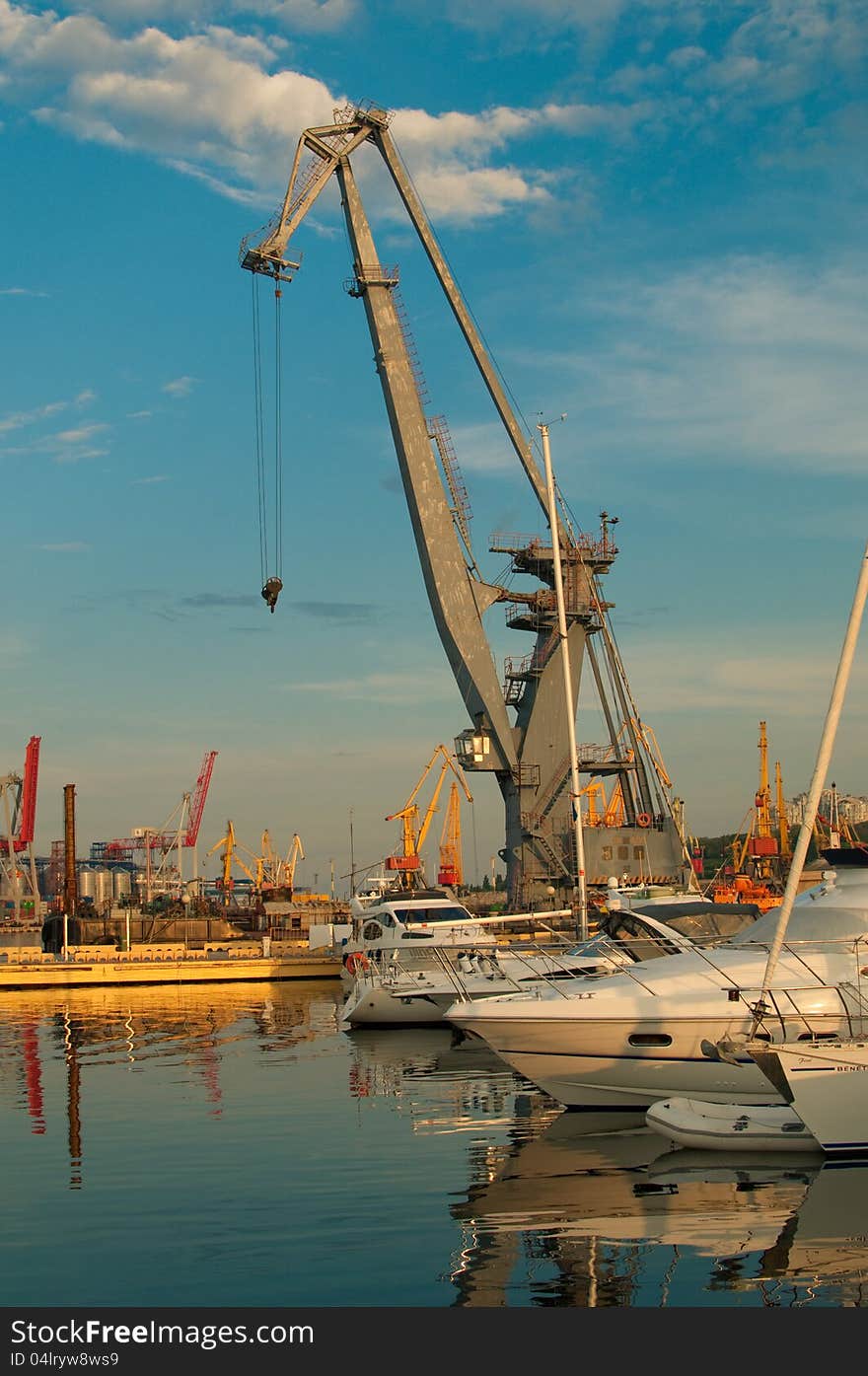 Port cranes and yachts on a sunset