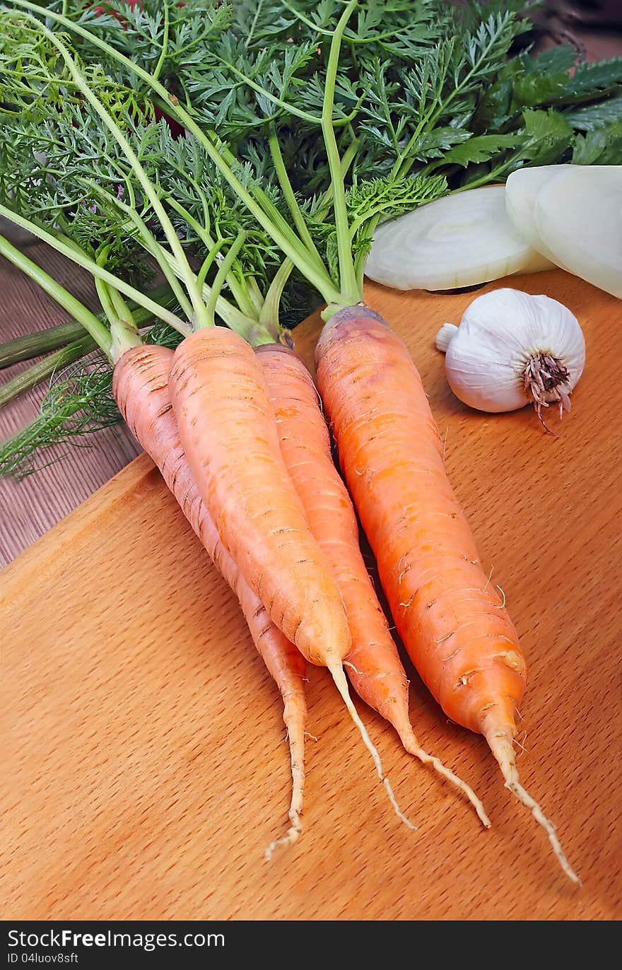 Fresh carrots on wooden board. Shot in a studio.