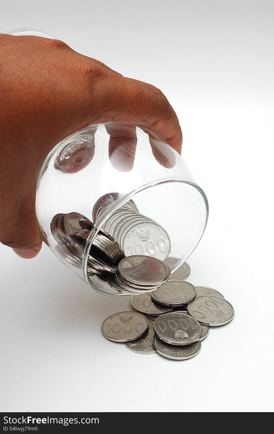 Coins spilling from the glass isolated on white background