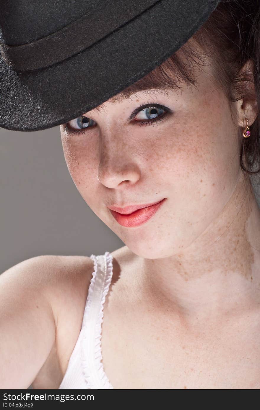 Close-up portrait of a beautiful girl with freckles and black hat. Close-up portrait of a beautiful girl with freckles and black hat