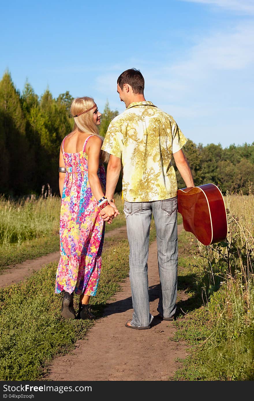 Young woman and man with guitar go on road