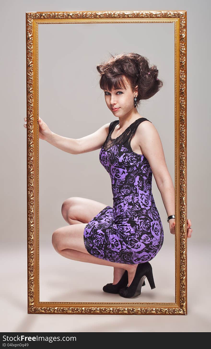 Beautiful girl posing in a violet dress, stilettos and pattern frame. Beautiful girl posing in a violet dress, stilettos and pattern frame