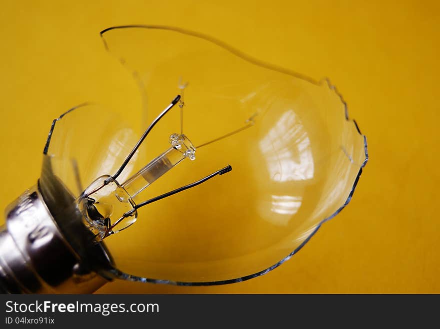 Broken light bulb on yellow background